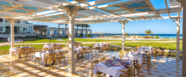 Auf der eleganten Außenterrasse des Restaurantbereichs schweift der Blick über die Anlage bis zum Roten Meer, getragen von einer ruhigen, offenen Atmosphäre im Freien.