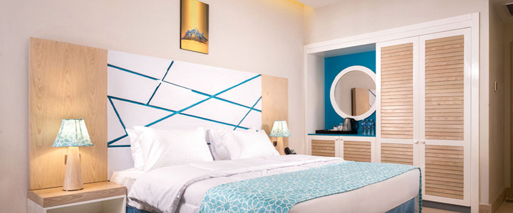 Die helle, moderne Suite mit Doppelzimmer in warmem Holzton und türkisen Akzenten wirkt freundlich und klar, mit ruhiger, harmonischer Raumgestaltung.