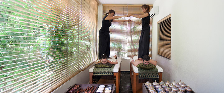 Traditionelle Paarmassage im Rodos Palace, bei der zwei Masseure eine entspannende Behandlung an einem Mann und einer Frau durchführen.